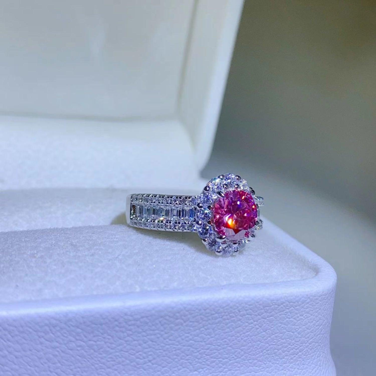 Elegant 1 carat moissanite ring with vibrant pink center stone surrounded by sparkling diamond accent stones, set in sterling silver.