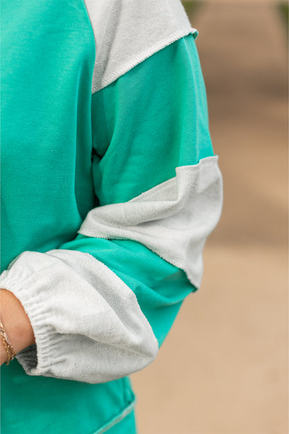 a person wearing a green and white shirt holding a cell phone