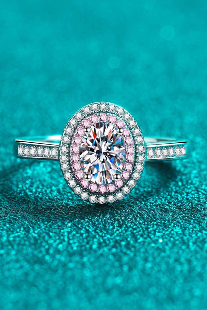 Sparkling oval-shaped diamond engagement ring with pave-set diamonds on a turquoise background.