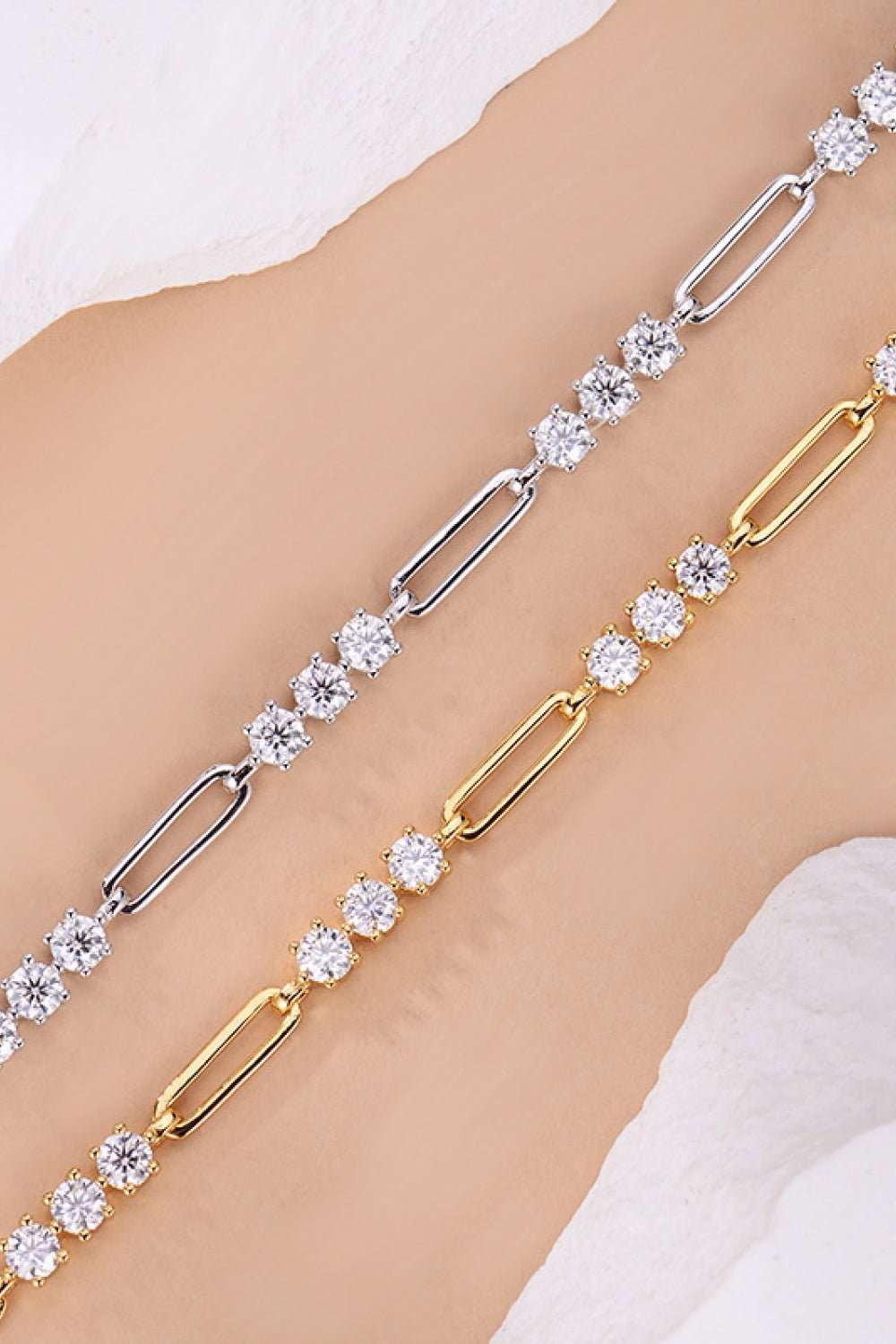 Elegant sterling silver and gold-tone moissanite bracelet with sparkling gemstones displayed on a female's arm.