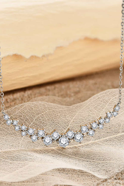 Elegant sterling silver necklace with 1.64 carat moissanite stones, displayed on sheer fabric against a beige desert backdrop.