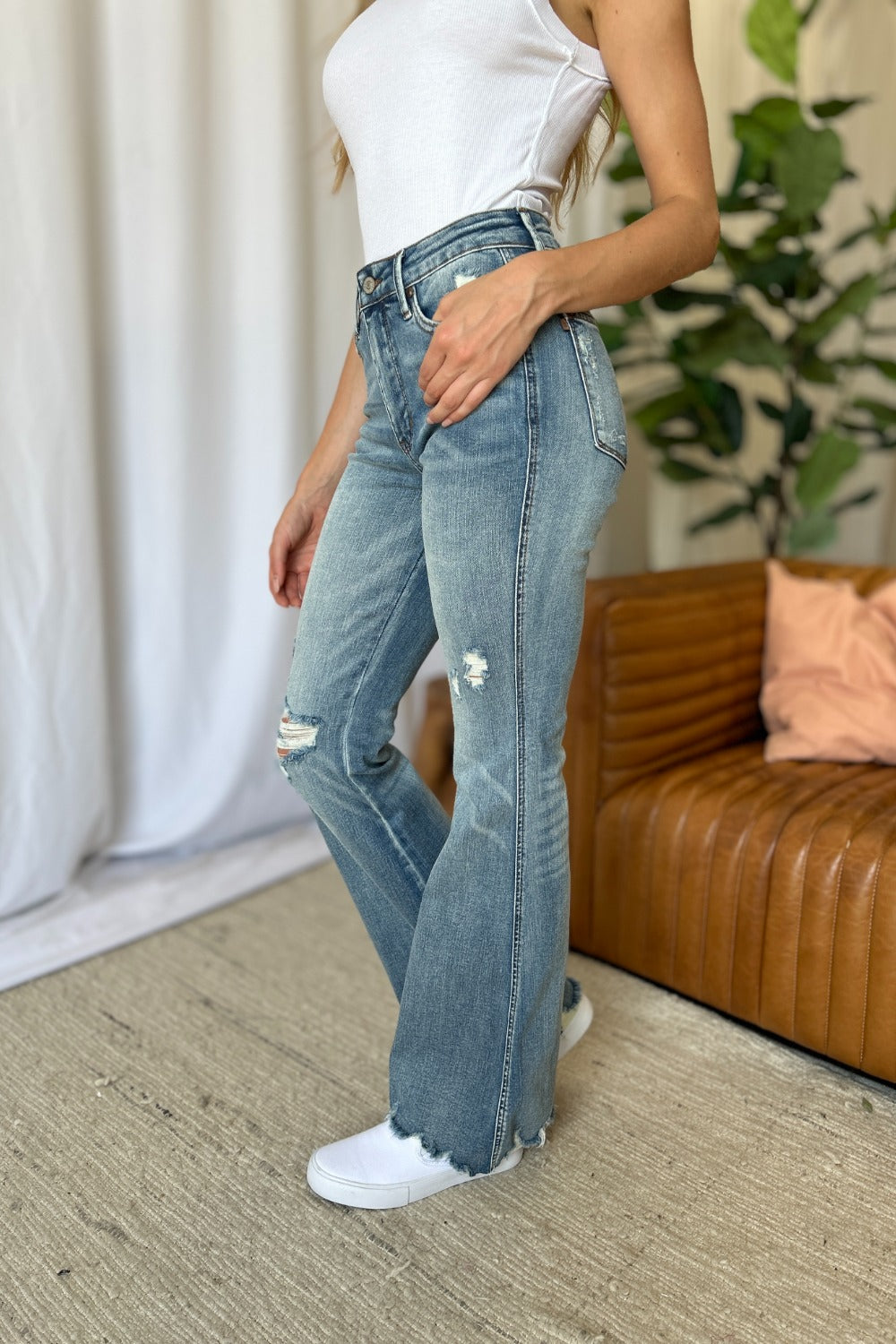 a woman standing in a living room wearing a pair of jeans