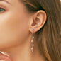 Sterling silver leaf-shaped earrings with sparkling moissanite stones, cascading delicately on a woman's ear.