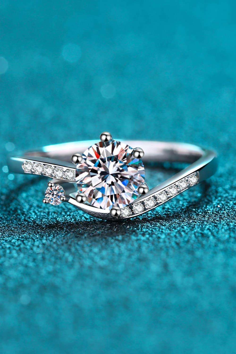 Elegant moissanite engagement ring with diamond accents on a teal blue background