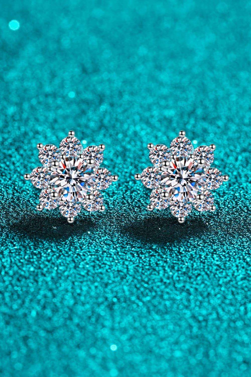 Sparkling diamond snowflake earrings on a shimmering teal background