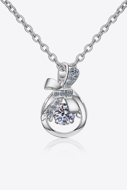 Elegant silver-tone necklace with sparkling crystal pendant, featuring a delicate bow accent and suspended stone for a chic, feminine look.