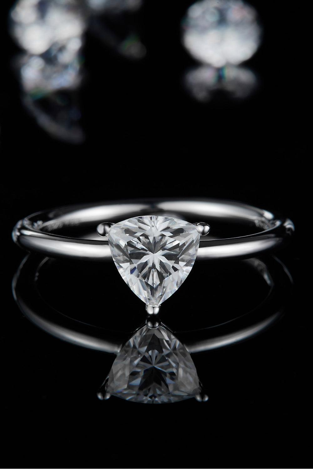 Sparkling heart-shaped moissanite solitaire ring on reflective surface