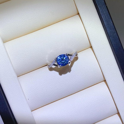 Elegant 1 carat moissanite crisscross 925 sterling silver ring displayed on a white background with a blue jewelry box.