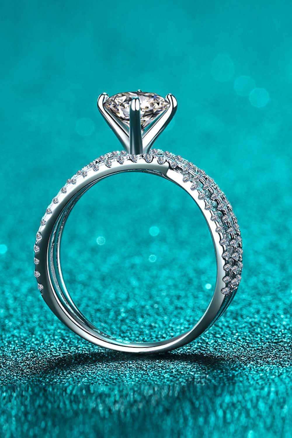 Elegant diamond engagement ring with sparkling center stone on a teal background