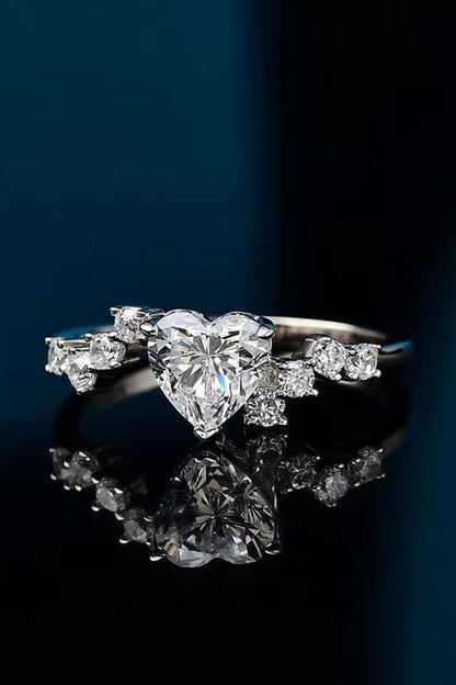 Elegant heart-shaped moissanite ring with sparkling side stones on dark background