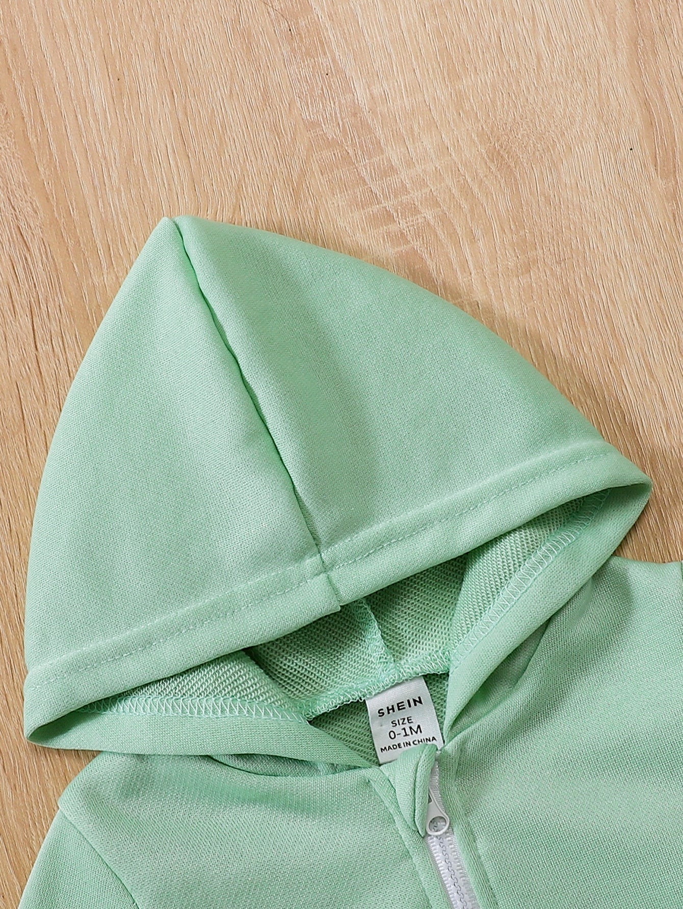 a close up of a green hoodie on a wooden surface