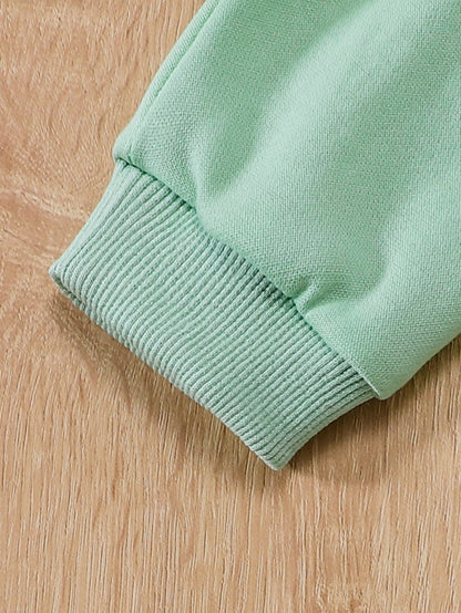 a green sweater laying on a wooden surface