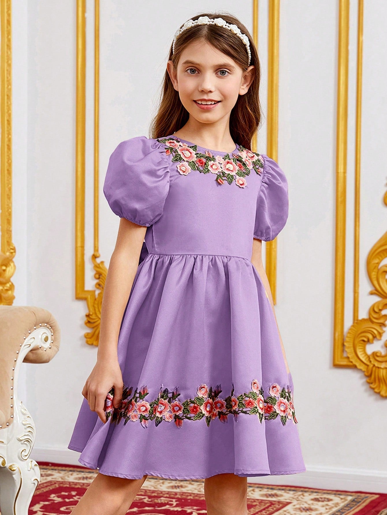 a little girl in a purple dress standing in a room