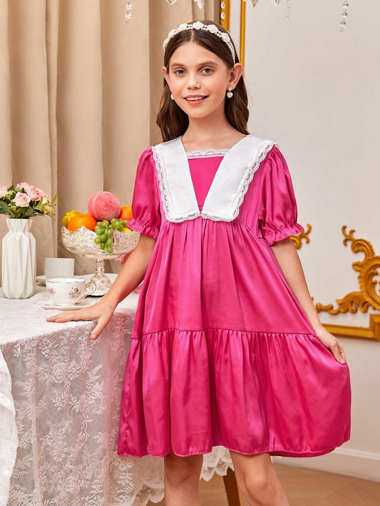 a little girl in a pink dress standing next to a table