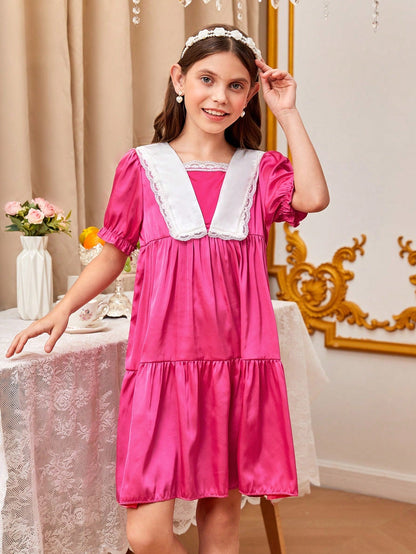 a little girl in a pink dress standing next to a table