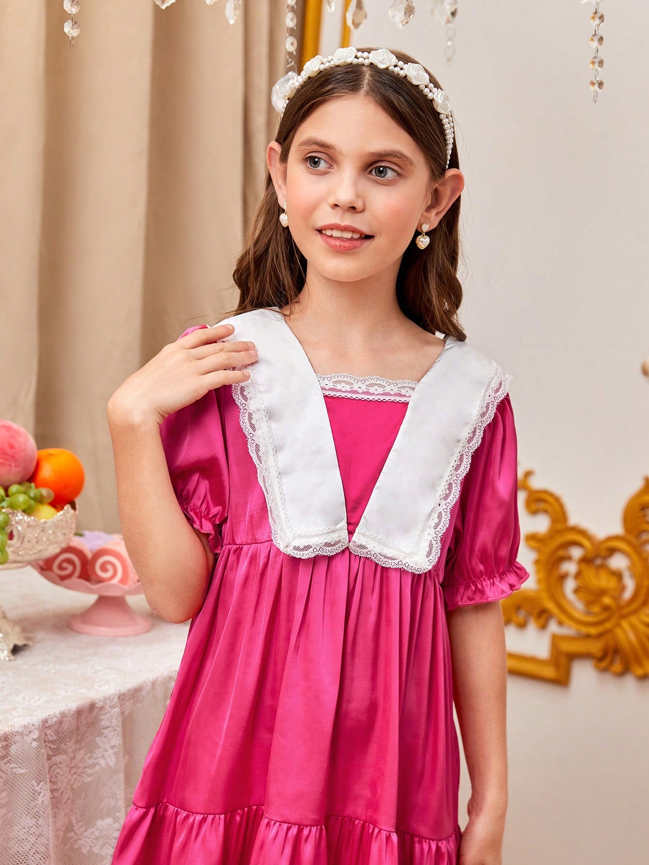 a little girl in a pink dress standing next to a table