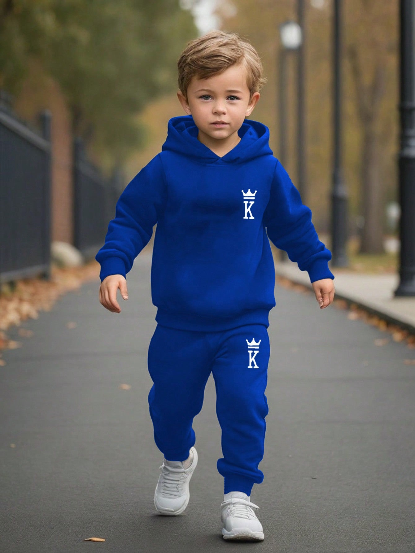 a young boy in a blue hoodie is walking down the street