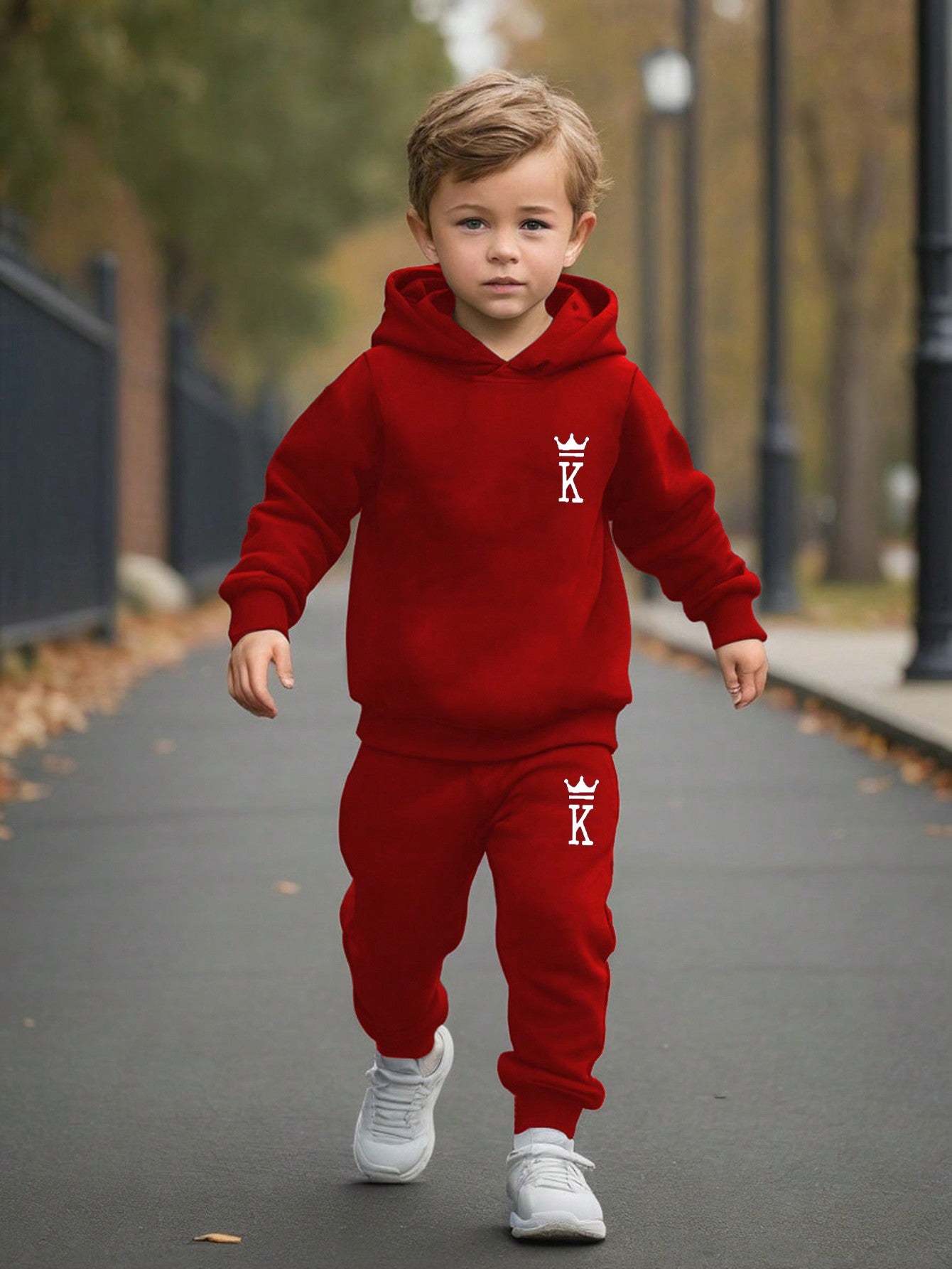 a young boy in a red hoodie is walking down the street