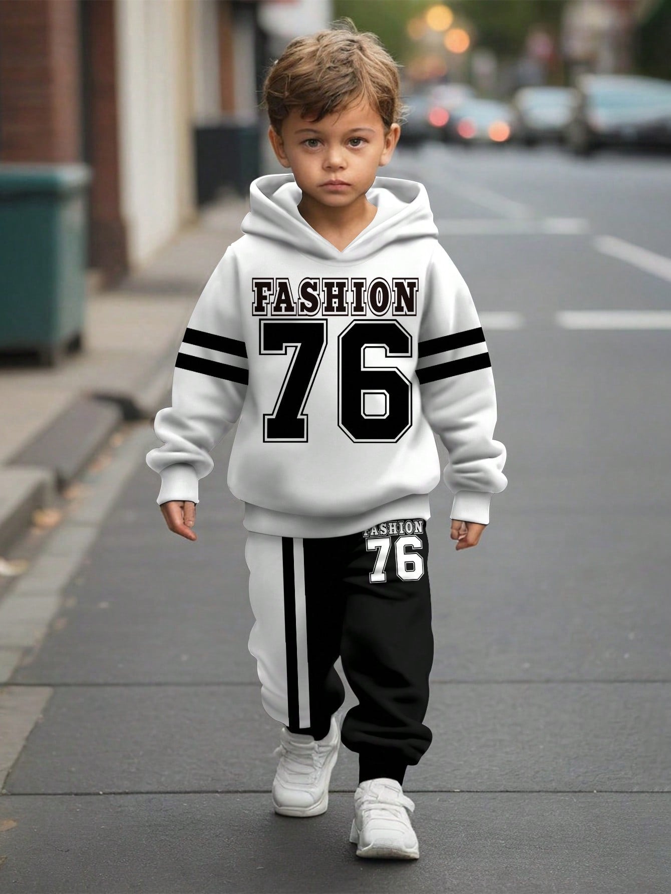 a young boy walking down a street wearing a white and black hoodie