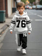 a young boy walking down a street wearing a white and black hoodie