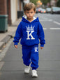 a young boy walking down a street wearing a blue hoodie