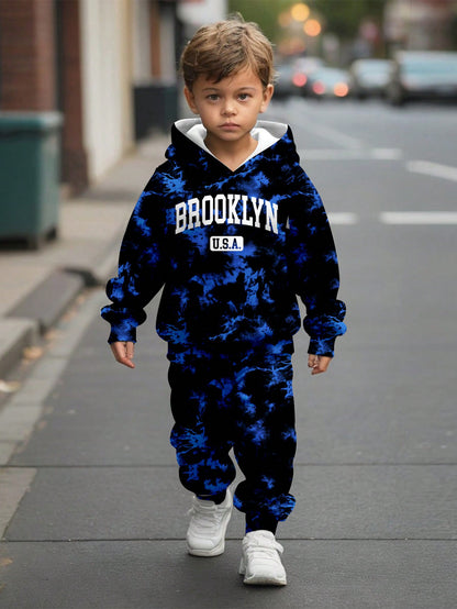 a young boy walking down a street wearing a blue and white hoodie