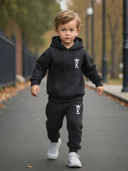 a young boy in a black hoodie is walking down the street