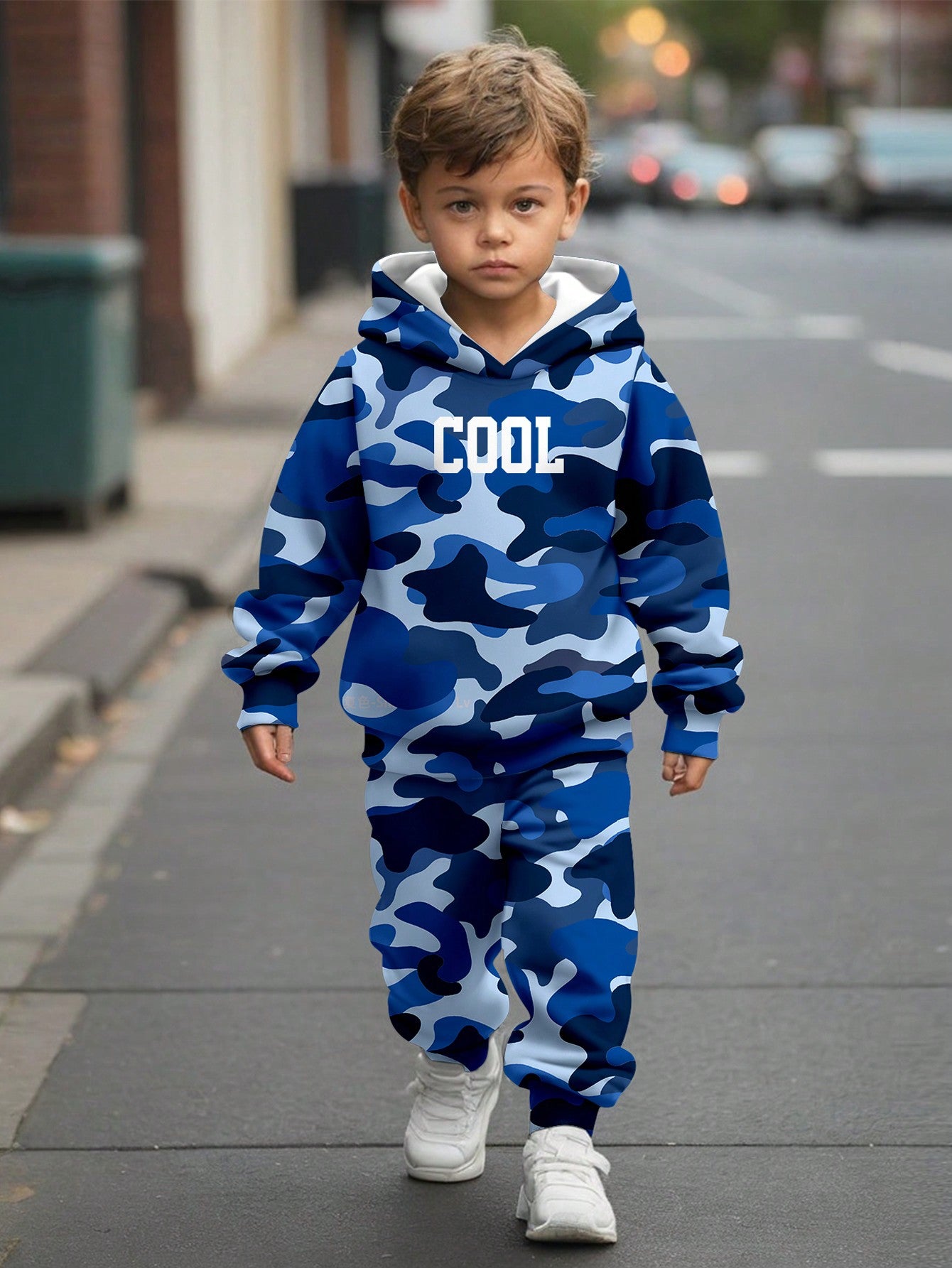 a young boy walking down a street wearing a blue camo hoodie