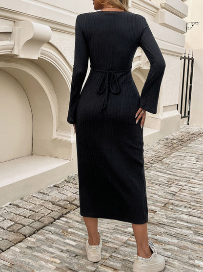 a woman in a black dress standing on a cobblestone street