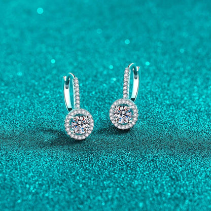 Sparkling round diamond earrings on a teal glitter background