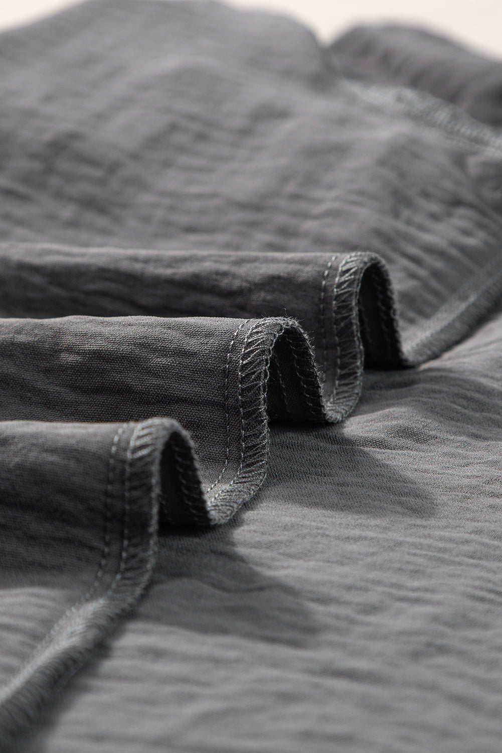 a close up of a bed with a gray bedspread