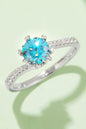 Elegant 1 Carat Moissanite 925 Sterling Silver Ring with a dazzling blue center stone and sparkling accents, showcased on a light green background.