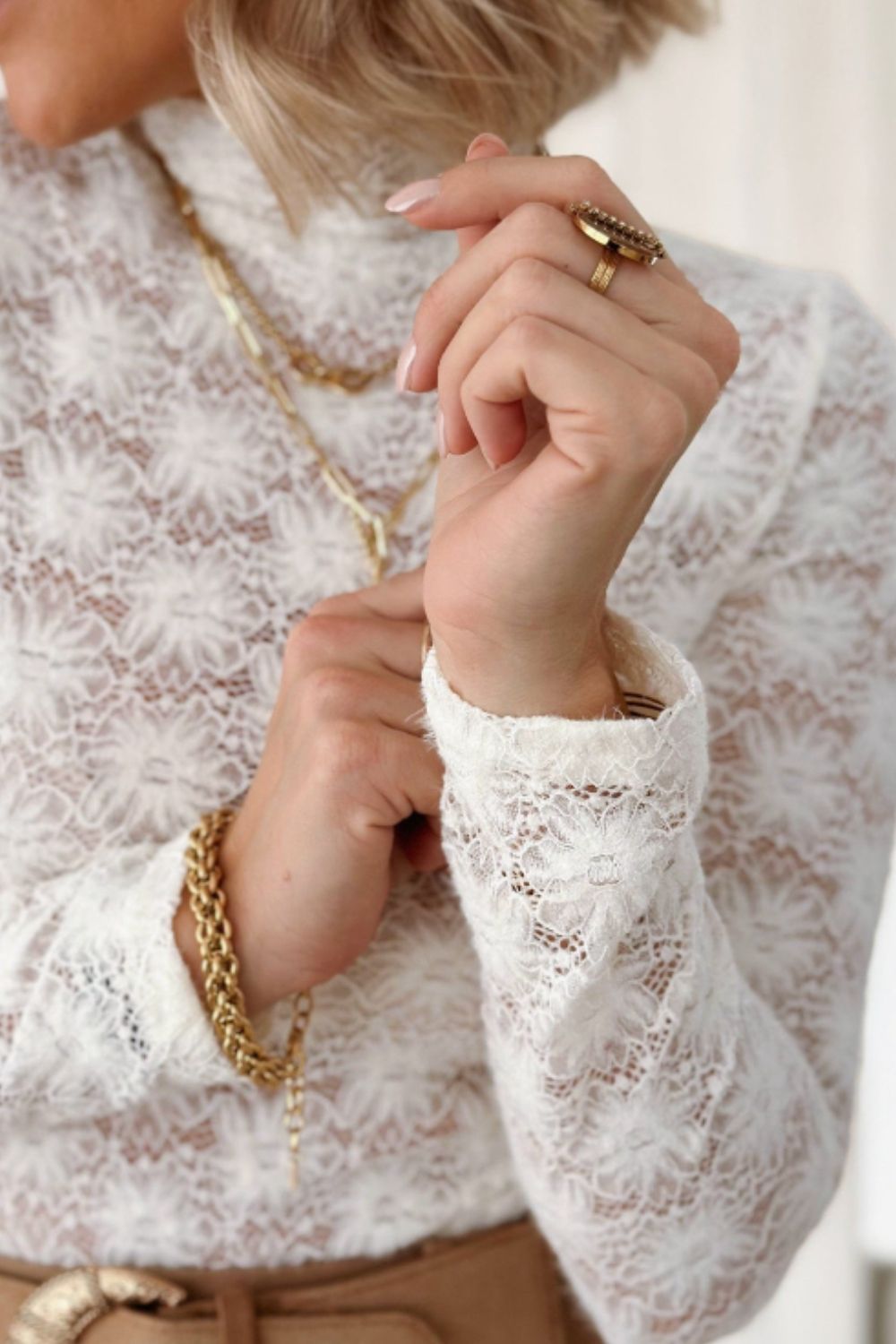 a woman wearing a white blouse and a gold necklace