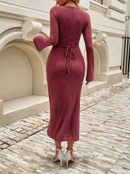 a woman in a red sweater dress is standing on a cobblestone street