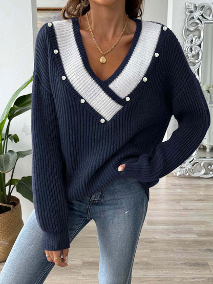 a woman wearing a sweater with pearls on the shoulders