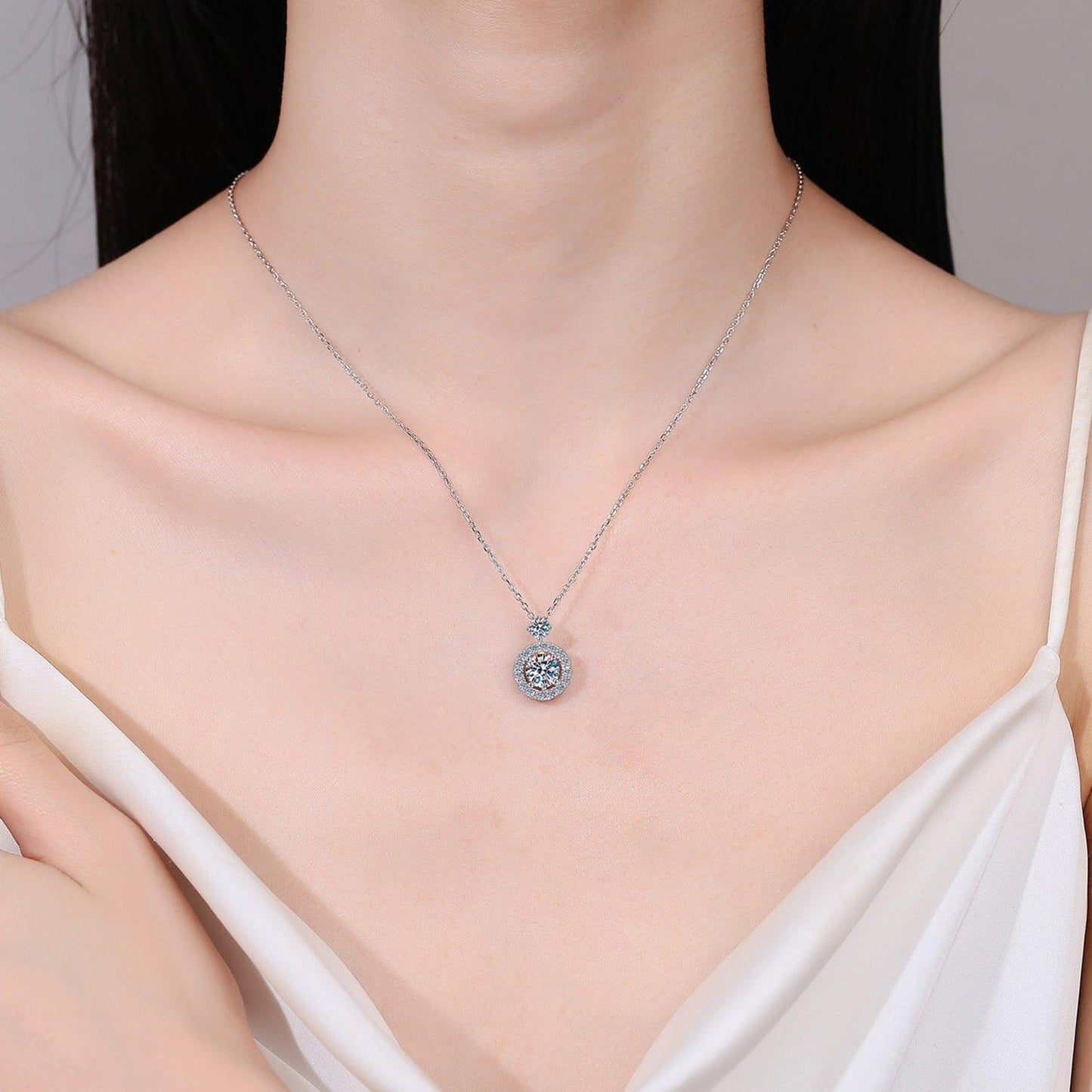 Elegant 925 sterling silver necklace with sparkling 1 carat moissanite pendant, showcased on a female model's delicate neck and shoulders.