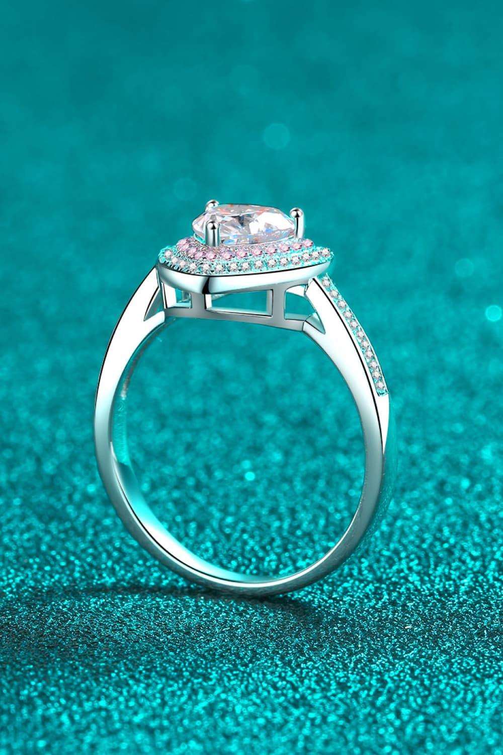 Elegant heart-shaped moissanite solitaire ring on a teal sparkling background