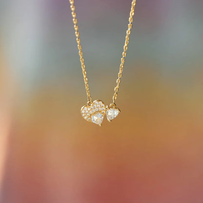 a gold necklace with two hearts hanging from it