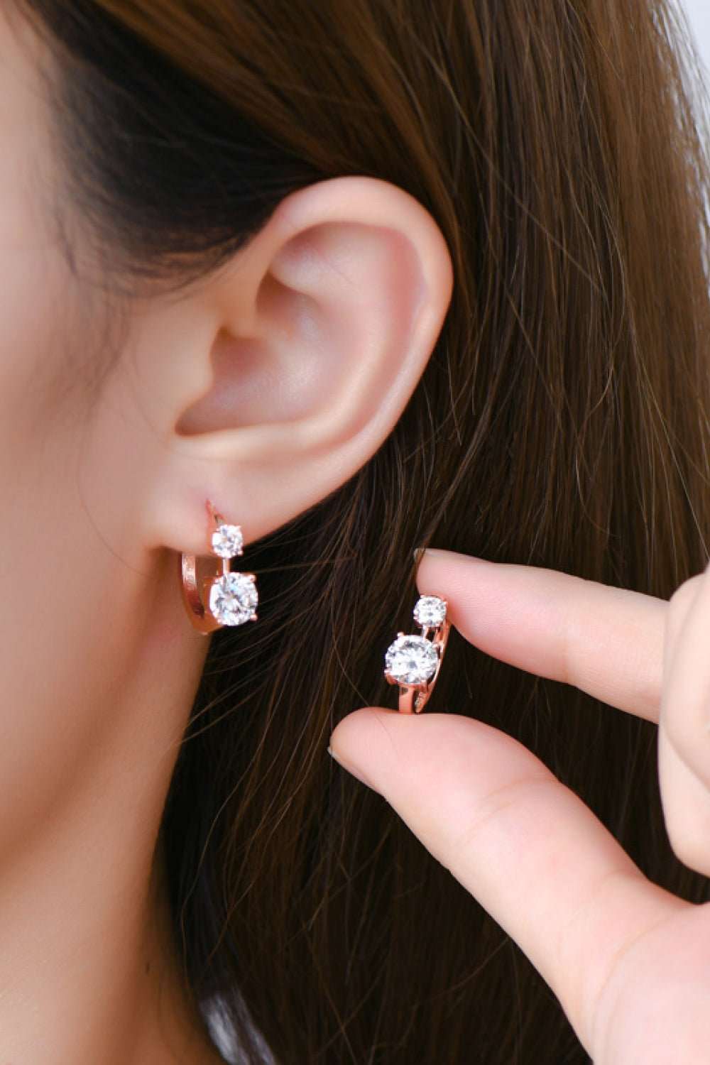 Elegant 925 silver earrings with sparkling moissanite stones in close-up view on a dark-haired model.