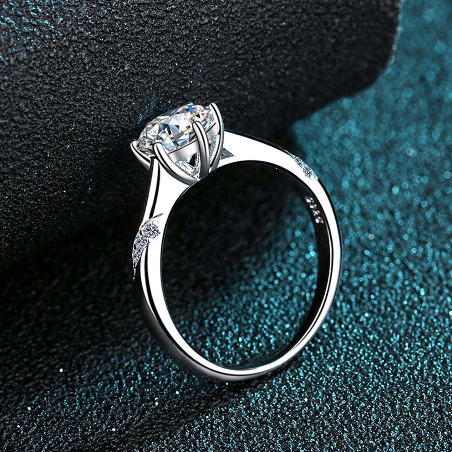 Elegant 1 Carat Moissanite 925 Sterling Silver Ring on a sparkly teal-colored background