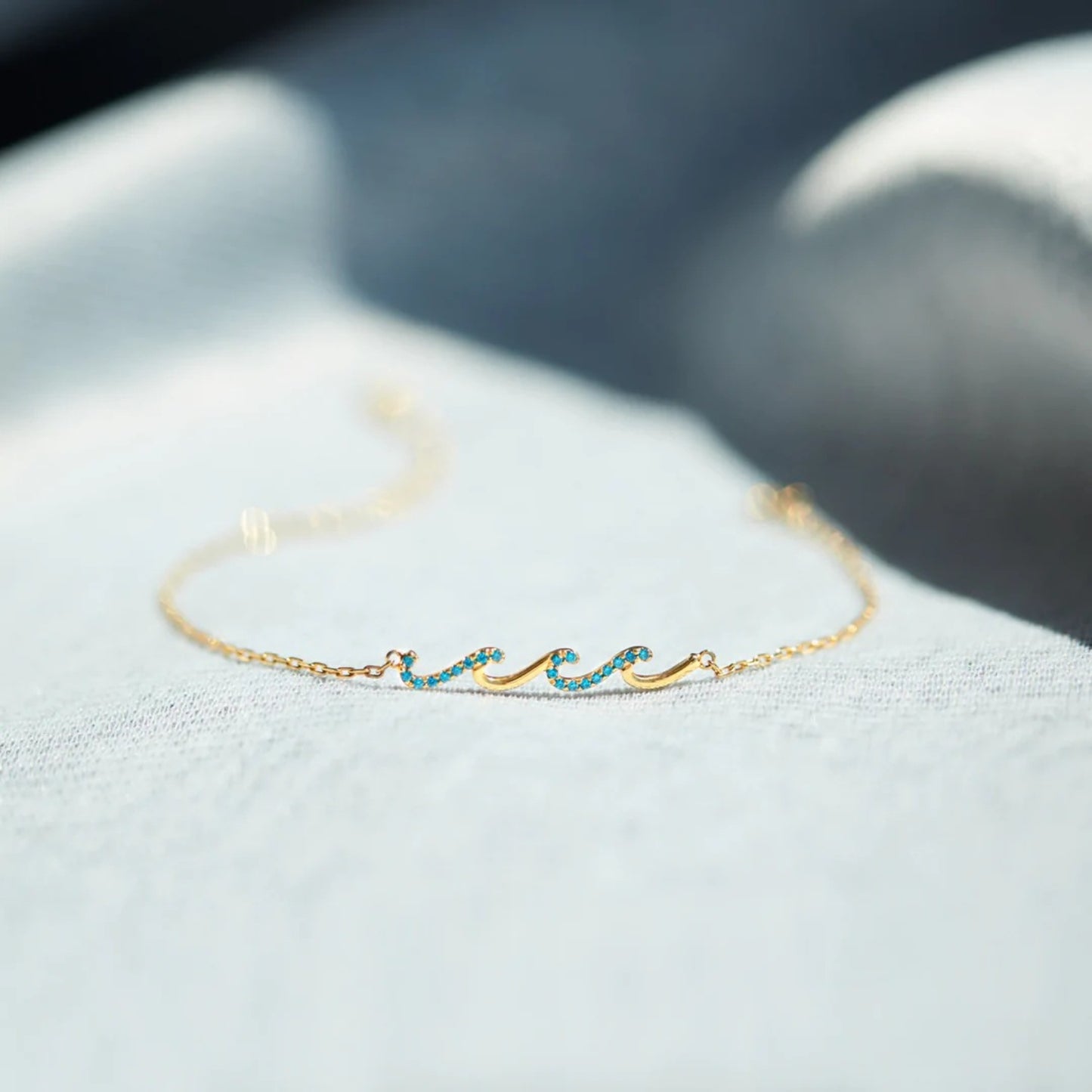 a close up of a gold bracelet with a wave on it