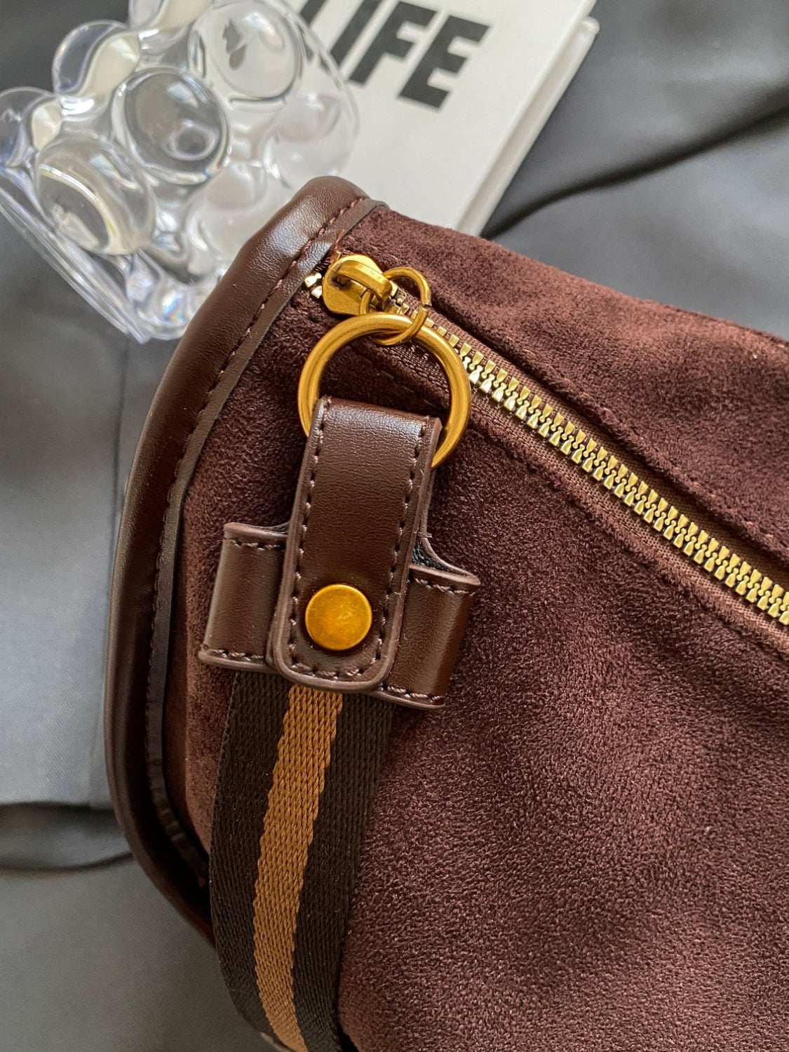 a brown purse sitting on top of a bed