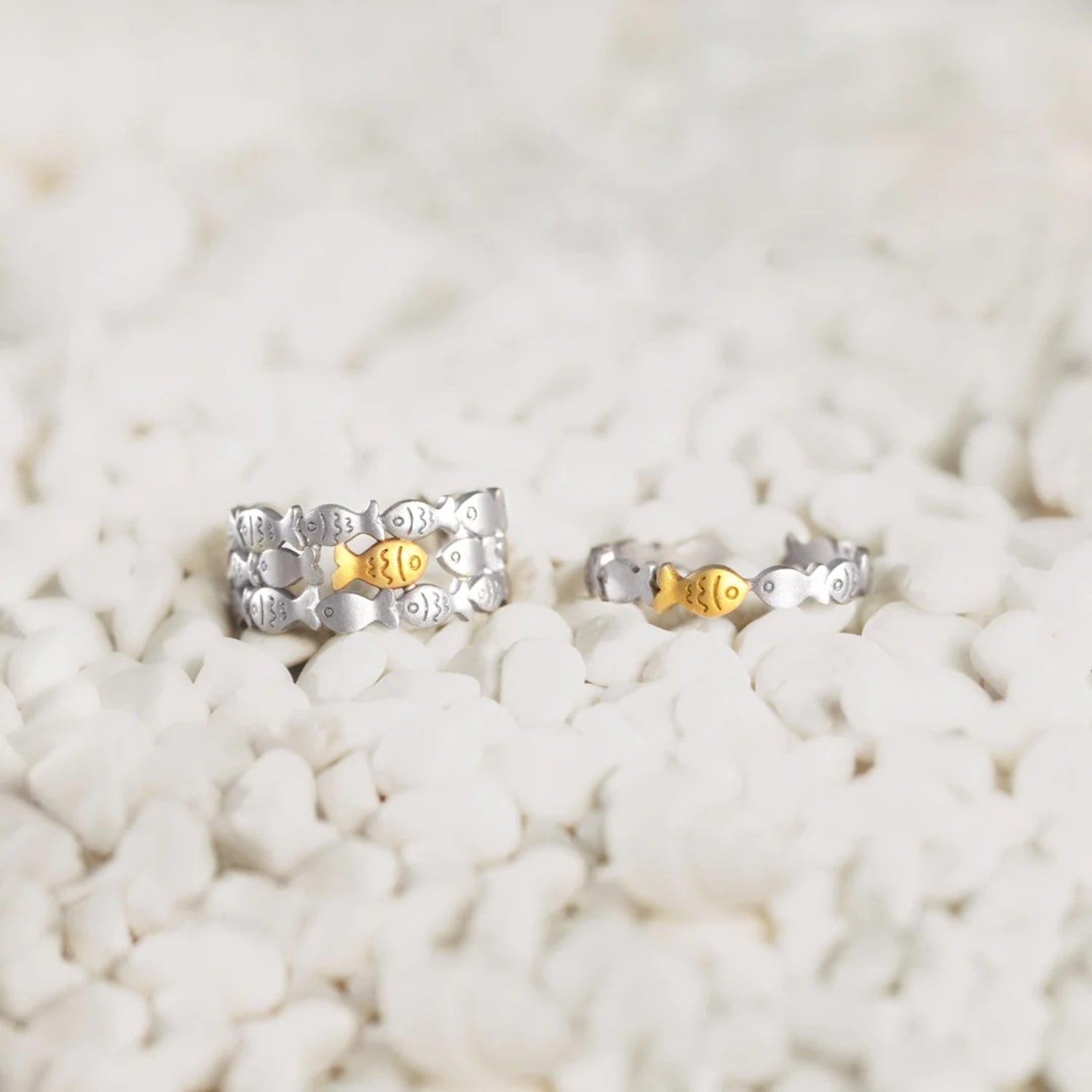 a pair of silver and gold earrings sitting on a pile of rocks