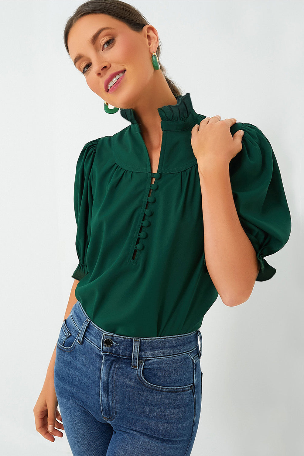 a woman wearing a green blouse and jeans