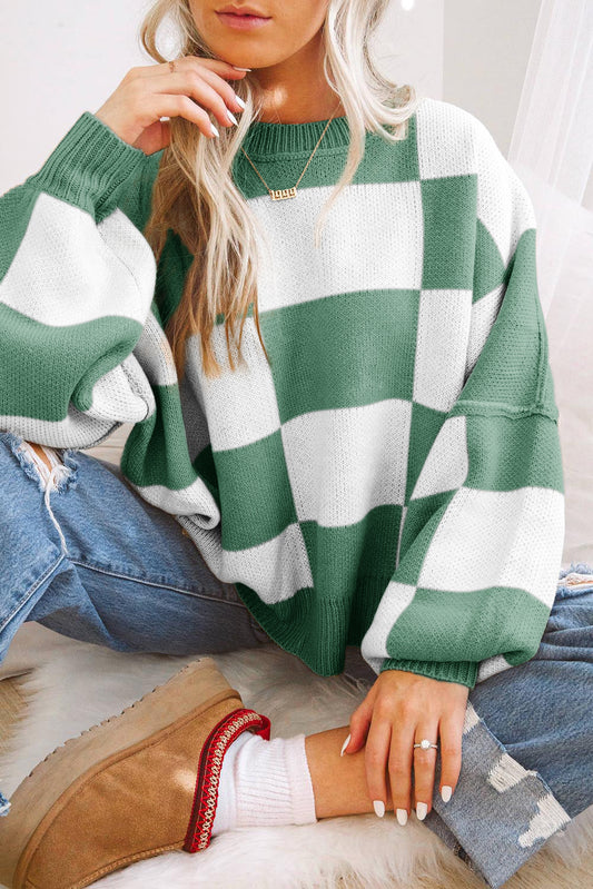 a woman sitting on a bed wearing a green and white checkered sweater