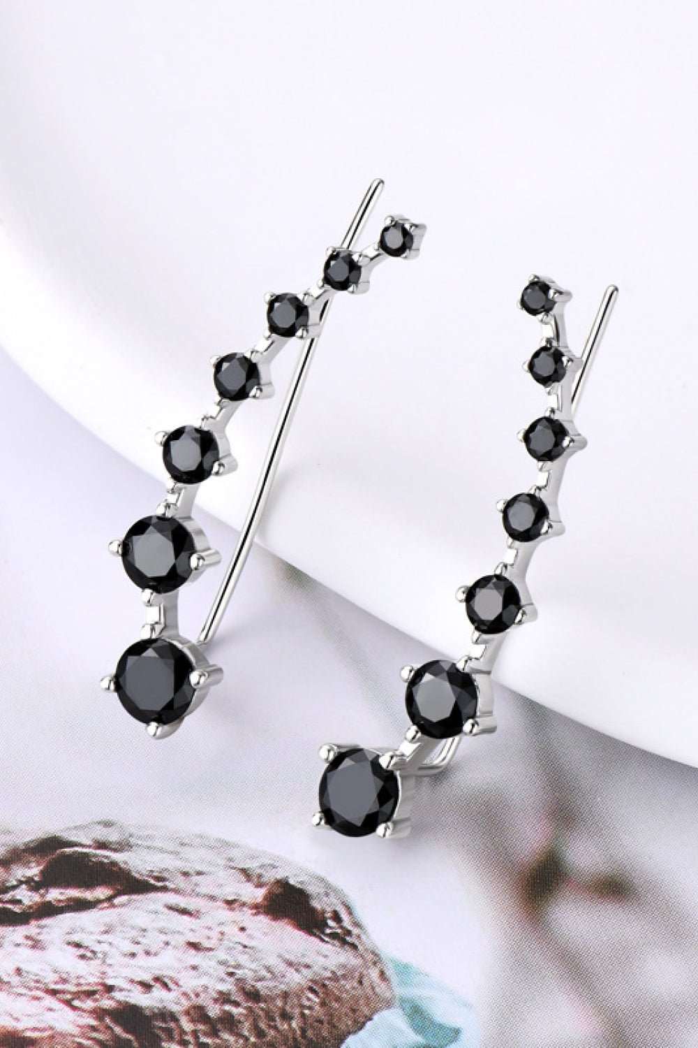 Elegant sterling silver moissanite earrings with a captivating line of black stones, displayed on a white background.