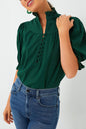 a woman wearing a green blouse and jeans