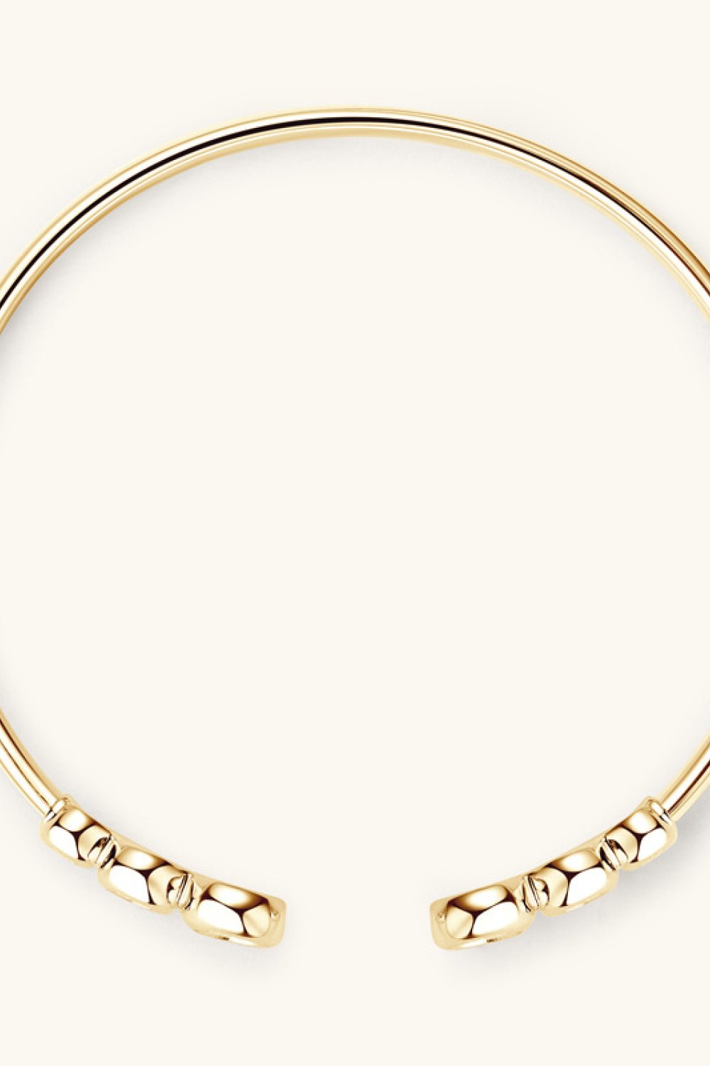 Elegant gold open bangle bracelet with sleek beaded design, showcased against a plain white background.