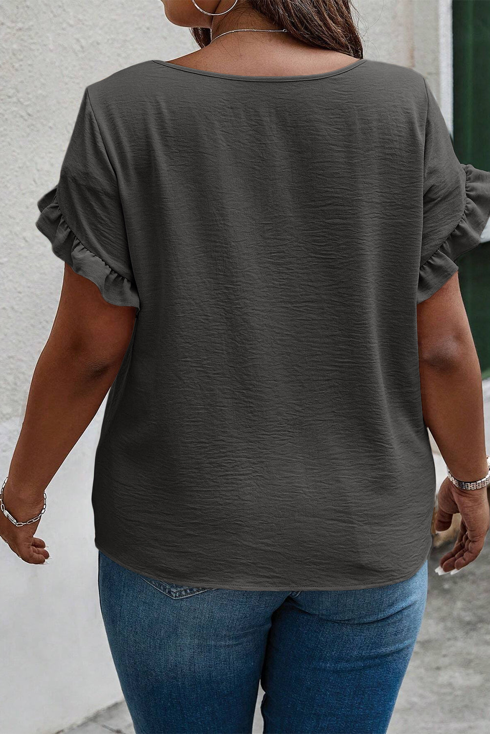 a woman walking down a street wearing a gray top