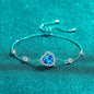 Elegant heart-shaped blue gemstone bracelet with sparkling accents, resting on a vibrant teal background.